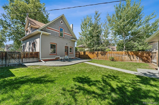 rear view of property featuring a fenced backyard, a yard, and a patio