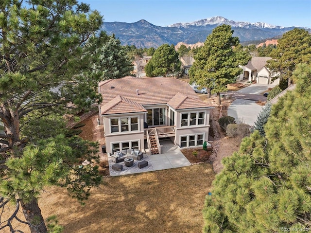 rear view of property with a tile roof, a patio, a mountain view, and stucco siding