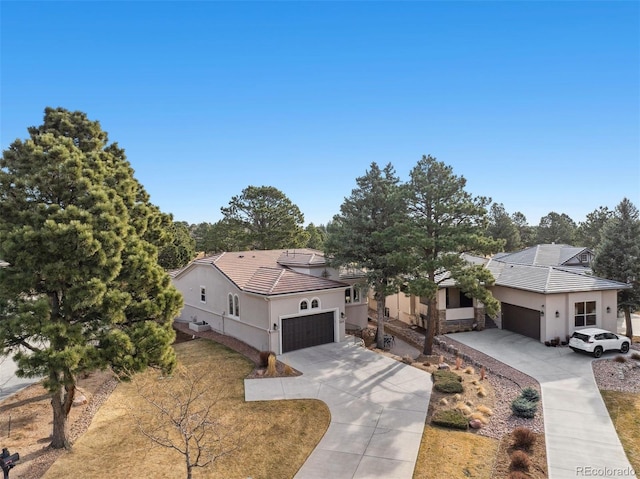 view of front of property with a tiled roof, an attached garage, driveway, and stucco siding