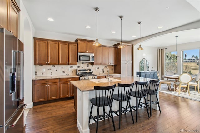 kitchen with stainless steel appliances, dark wood finished floors, and brown cabinetry