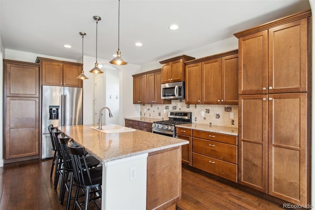 kitchen featuring a sink, tasteful backsplash, dark wood finished floors, appliances with stainless steel finishes, and brown cabinetry