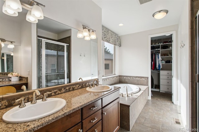 full bath featuring a sink, a walk in closet, a bath, and a shower stall