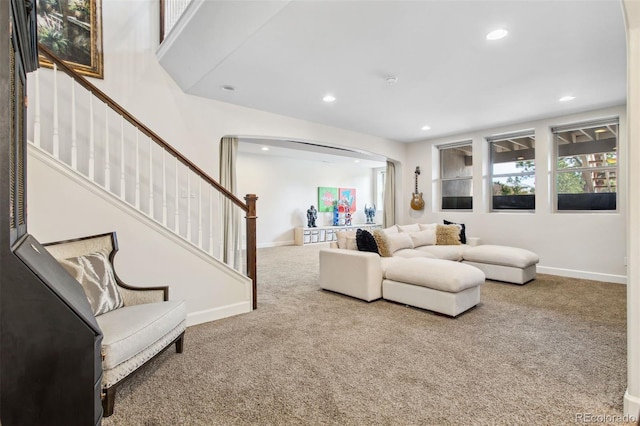 carpeted living area with recessed lighting, stairway, baseboards, and arched walkways