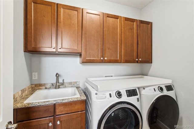 washroom featuring washing machine and clothes dryer, cabinet space, and a sink