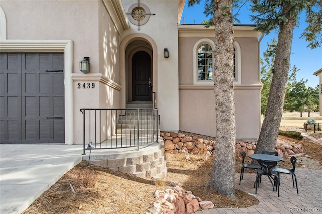 entrance to property with concrete driveway, a garage, and stucco siding