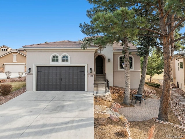 mediterranean / spanish-style home with stucco siding, a garage, driveway, and a tile roof