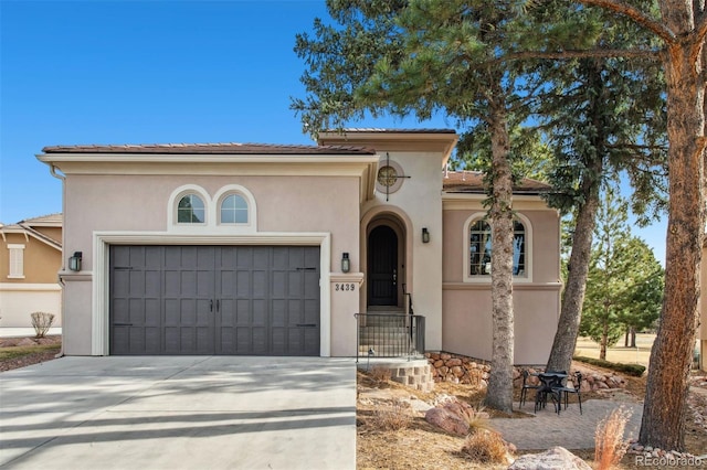 mediterranean / spanish house with a garage, driveway, and stucco siding