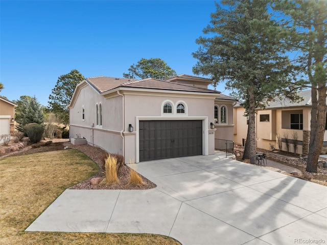 mediterranean / spanish-style house with a front yard, stucco siding, concrete driveway, a garage, and a tile roof