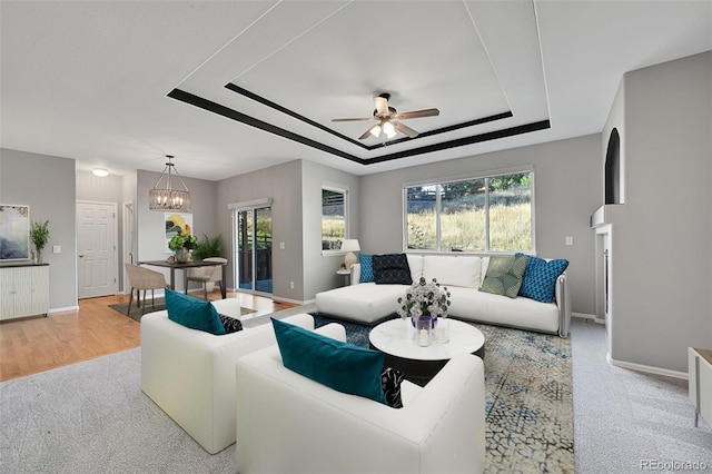 living room featuring ceiling fan with notable chandelier, a wealth of natural light, and light hardwood / wood-style flooring