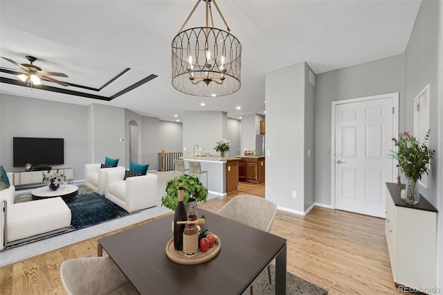 living room featuring ceiling fan with notable chandelier and light hardwood / wood-style floors