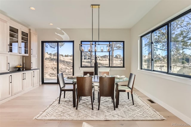 dining room with light wood-type flooring and an inviting chandelier