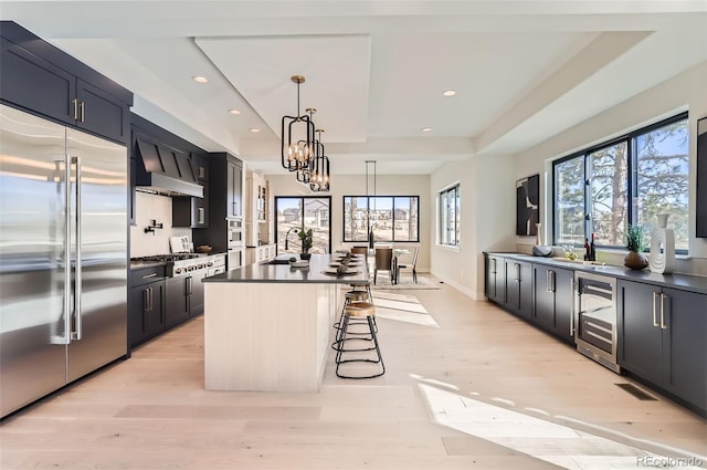 kitchen featuring a kitchen bar, a tray ceiling, a kitchen island, pendant lighting, and stainless steel appliances