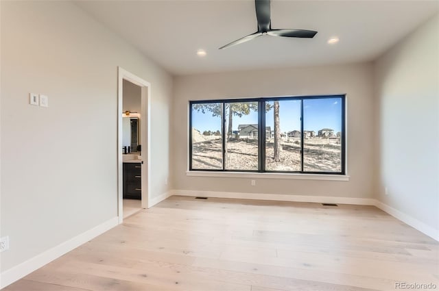 empty room with ceiling fan and light hardwood / wood-style flooring