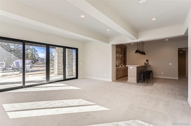 unfurnished living room with light carpet, wet bar, and beamed ceiling