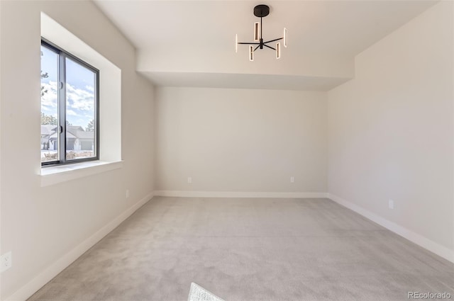 spare room with light colored carpet and a chandelier