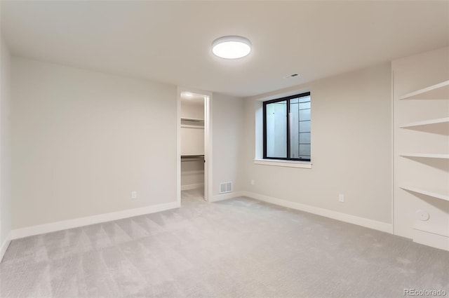 unfurnished bedroom with a walk in closet, light colored carpet, and a closet