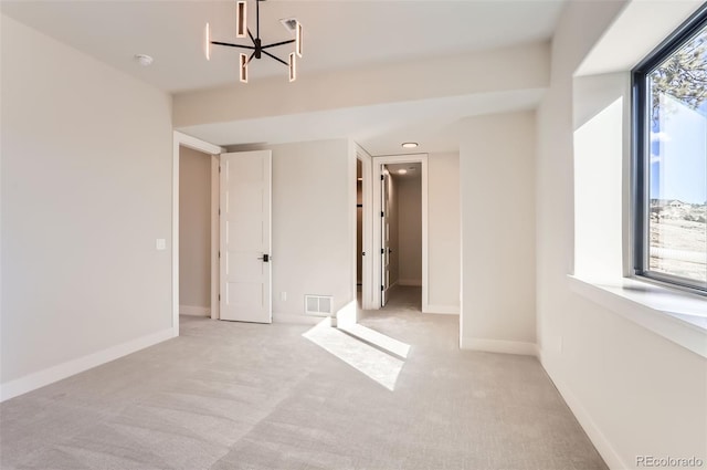 unfurnished bedroom featuring multiple windows, a walk in closet, light carpet, and a chandelier