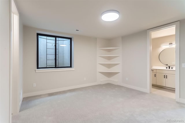 unfurnished bedroom with ensuite bathroom, sink, and light carpet