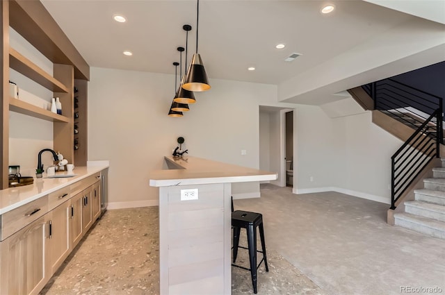 bar with hanging light fixtures, sink, and light brown cabinets