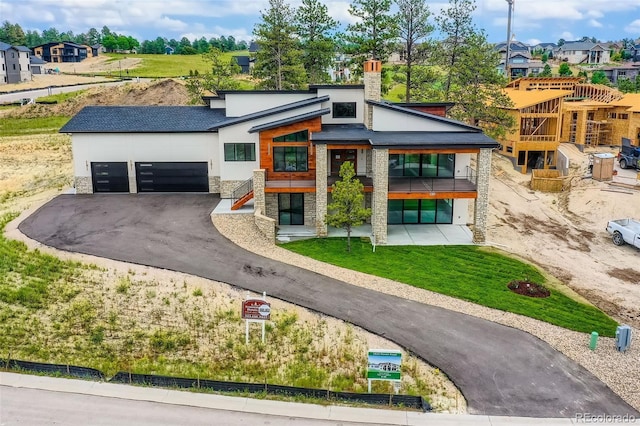 5820 Powell Rd, Parker, CO 80134 - modern home with stone siding, asphalt driveway, an attached garage, stucco siding, and a chimney