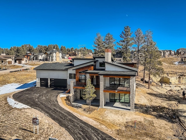 5820 Powell Rd, Parker, CO 80134 - contemporary house featuring a garage, a residential view, stone siding, asphalt driveway, and a chimney