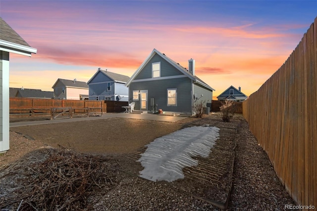 back house at dusk featuring a patio area and central AC