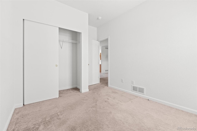 unfurnished bedroom with a closet and light colored carpet