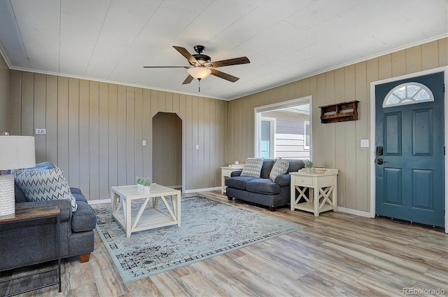 living room featuring arched walkways, a healthy amount of sunlight, ceiling fan, and crown molding