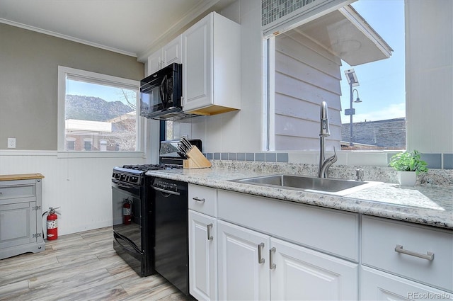 kitchen with crown molding, light wood-style flooring, white cabinets, black appliances, and a sink