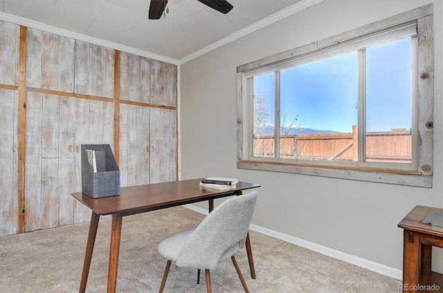 carpeted office featuring wooden walls, baseboards, ornamental molding, and ceiling fan
