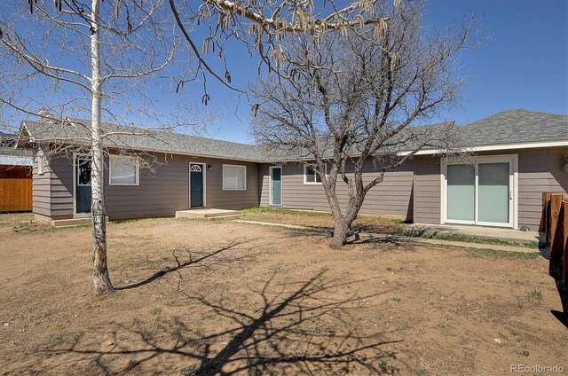 back of property with fence and a shingled roof