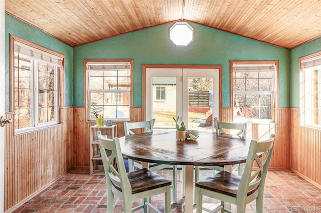 dining space featuring wood ceiling, lofted ceiling, and wood walls