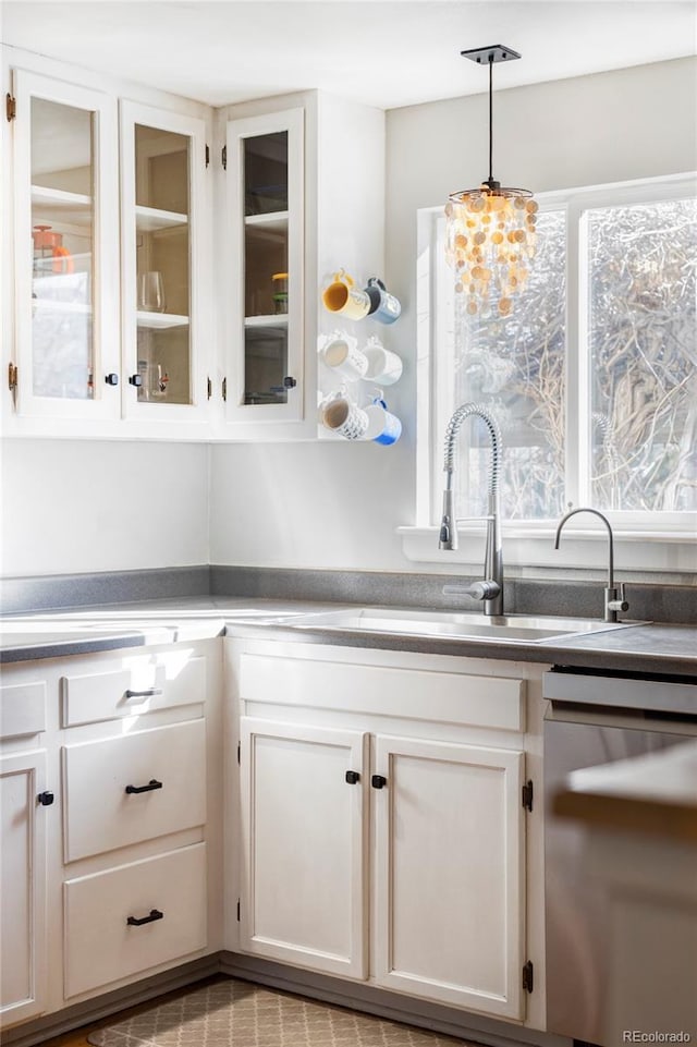 kitchen featuring white cabinets, hanging light fixtures, stainless steel dishwasher, and sink