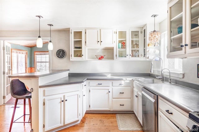 kitchen featuring hanging light fixtures, stainless steel appliances, a breakfast bar area, white cabinetry, and sink