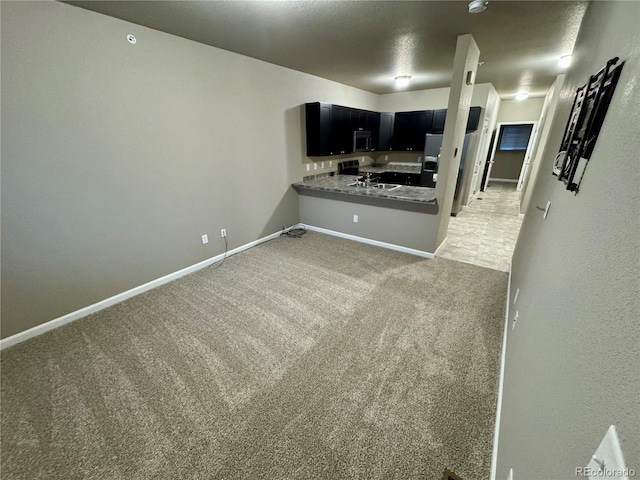 interior space featuring kitchen peninsula, sink, carpet, and stainless steel appliances