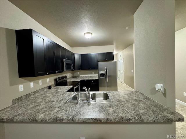 kitchen featuring kitchen peninsula, light stone counters, a textured ceiling, stainless steel appliances, and sink