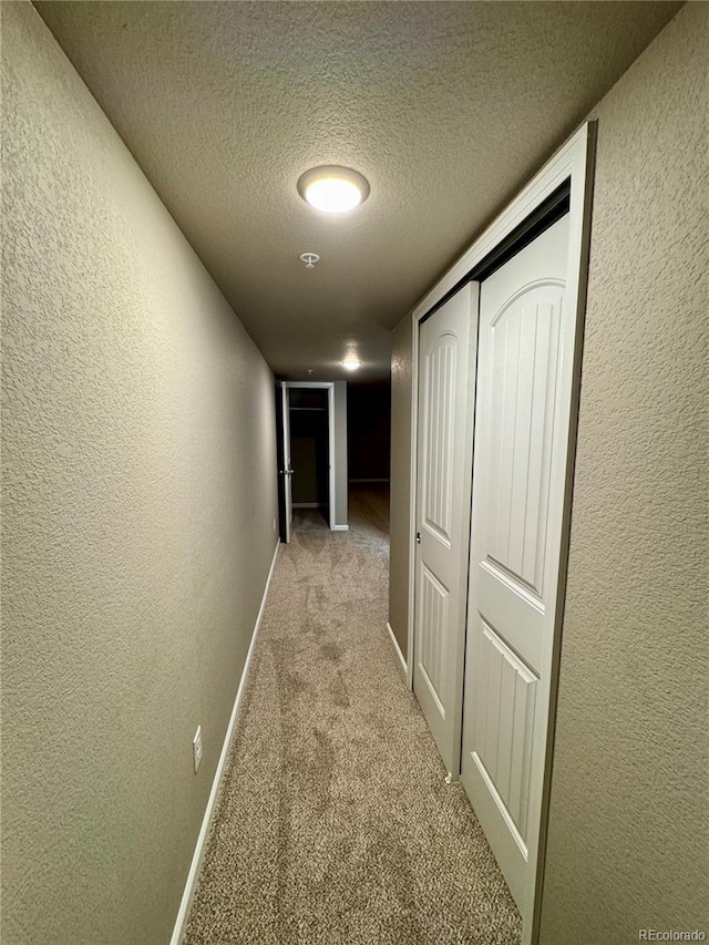 corridor with light colored carpet and a textured ceiling