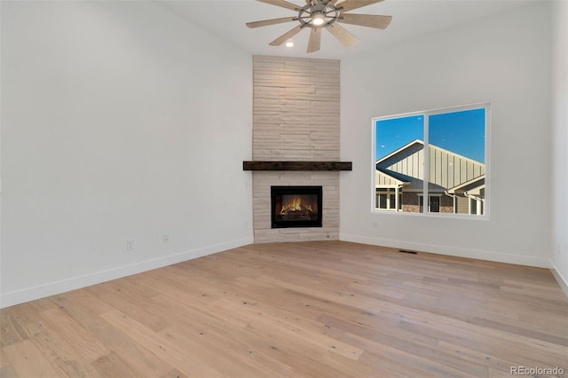 unfurnished living room featuring a tile fireplace, light wood-type flooring, and ceiling fan