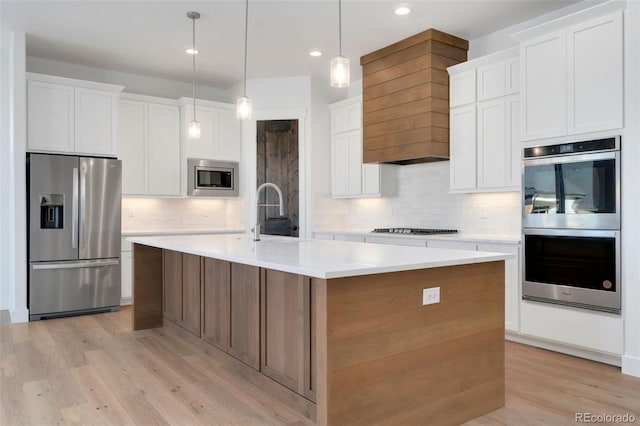 kitchen featuring appliances with stainless steel finishes, sink, a kitchen island with sink, and white cabinets