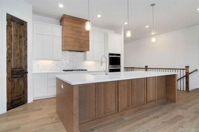 kitchen with white cabinetry, sink, and a spacious island