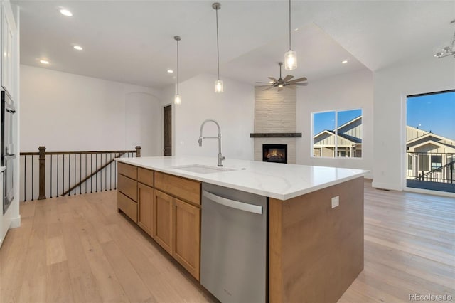 kitchen with pendant lighting, sink, light stone counters, a center island with sink, and stainless steel dishwasher