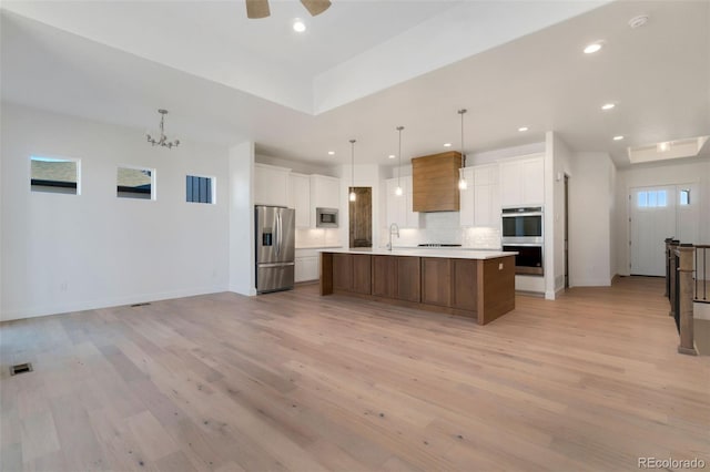 kitchen featuring a spacious island, stainless steel appliances, hanging light fixtures, and white cabinets