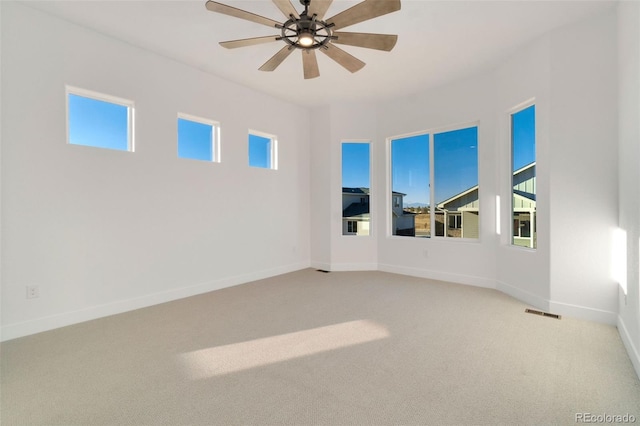 spare room featuring a wealth of natural light, light colored carpet, and ceiling fan