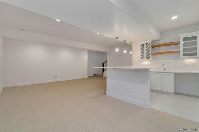 kitchen with pendant lighting, sink, white cabinetry, backsplash, and light colored carpet