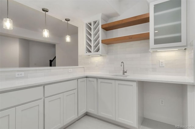 kitchen with decorative light fixtures, tasteful backsplash, sink, white cabinets, and light stone counters