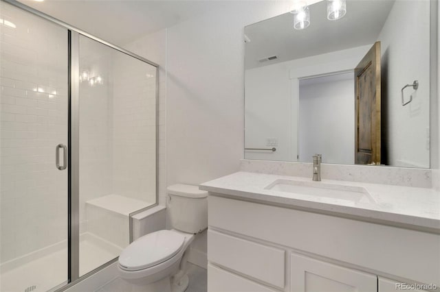 bathroom featuring vanity, a shower with shower door, and toilet