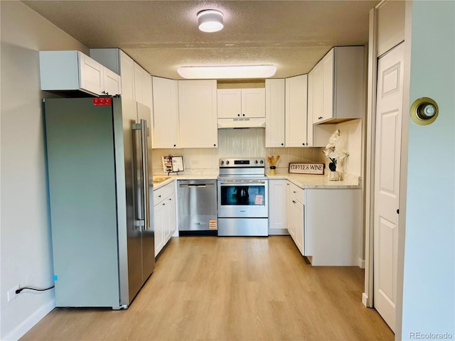 755 S Alton Way Unit 12C, Denver, CO 80247 - kitchen with stainless steel appliances, under cabinet range hood, light wood-style flooring, white cabinets, and a textured ceiling
