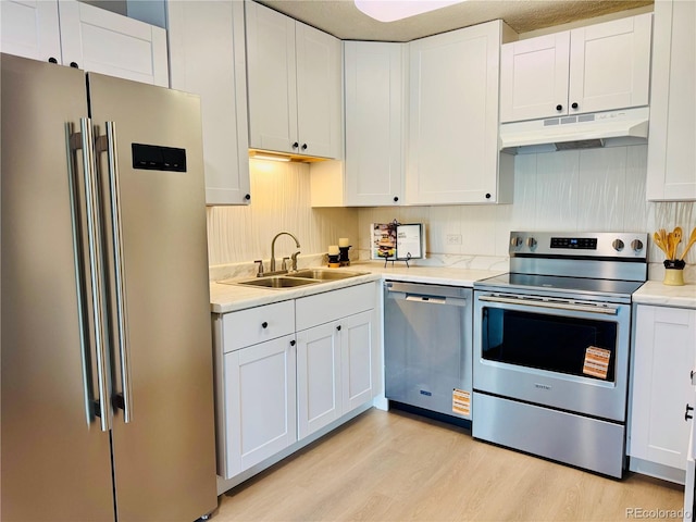 755 S Alton Way Unit 12C, Denver, CO 80247 - kitchen featuring appliances with stainless steel finishes, under cabinet range hood, a sink, light wood-style flooring, and light countertops