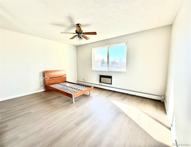755 S Alton Way Unit 12C, Denver, CO 80247 - unfurnished bedroom featuring wood finished floors, baseboards, a textured ceiling, baseboard heating, and a ceiling fan