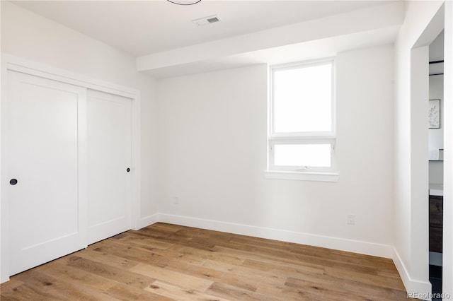 unfurnished bedroom with a closet and light hardwood / wood-style flooring